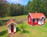 Rd stuga med vita knutar i idyllis...